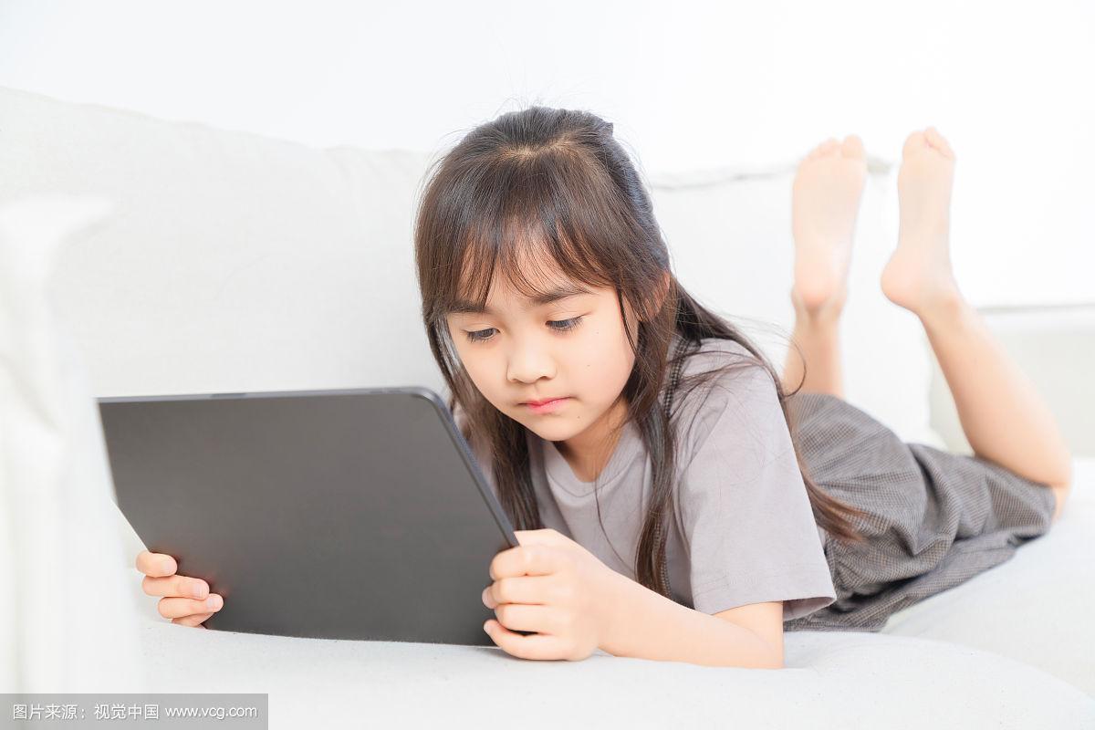 幼儿趴在沙发上玩平板电脑眼睛贴近屏幕