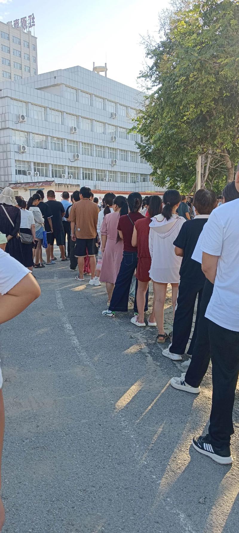 家长在小学门口排队报名划片入学场景