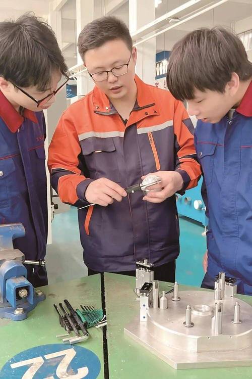 老产业工人给年轻学徒讲解工业零件精度要求