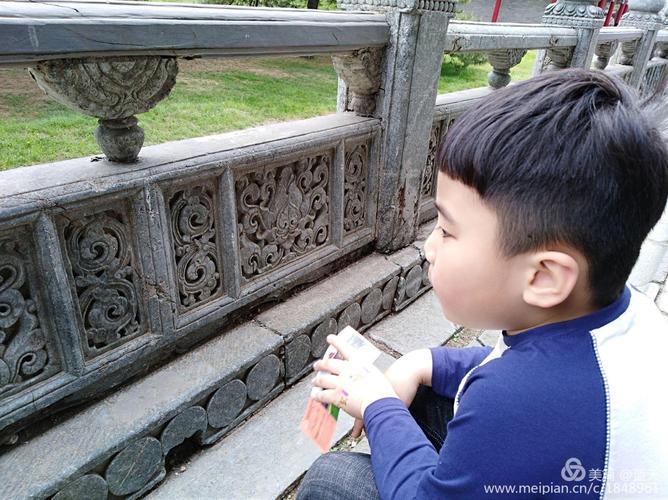 小朋友蹲在晋祠古门槛摸凹槽
