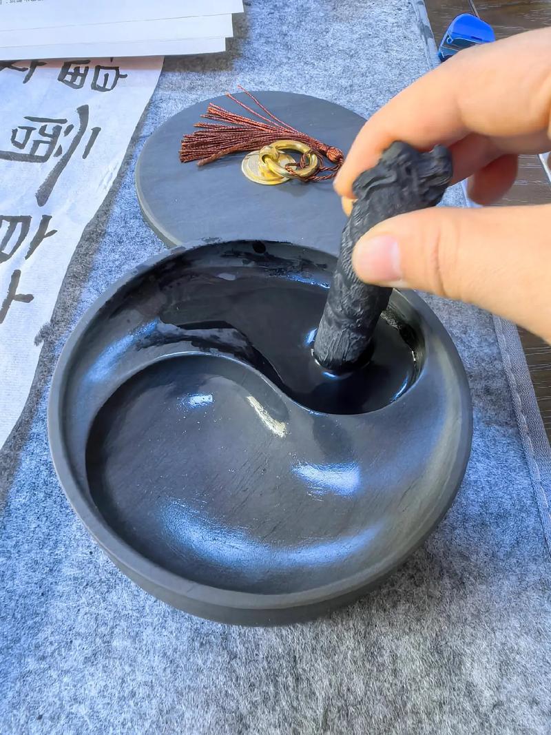 砚台上正在研磨的油烟墨条与水墨交融细节