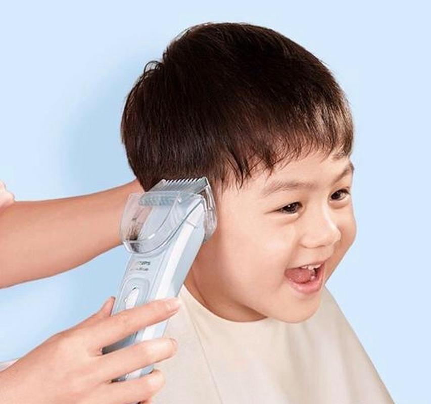 幼儿坐在儿童理发椅上玩玩具配合剪发实拍图