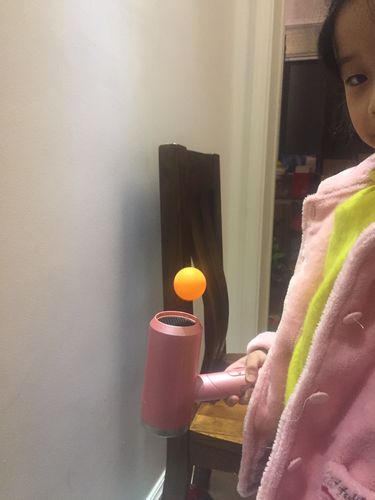 直播带货现场,主播正用吹风机演示风力悬浮乒乓球