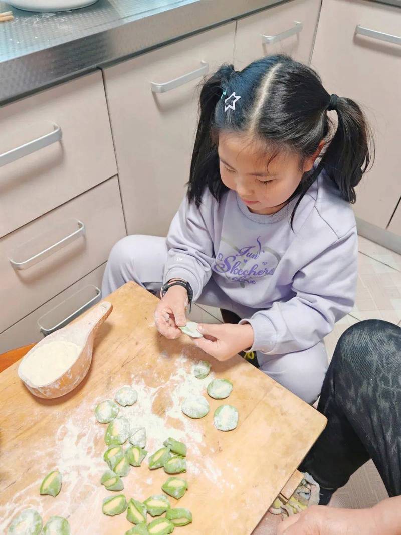 奶奶手把手教孩子包饺子满手面粉笑容