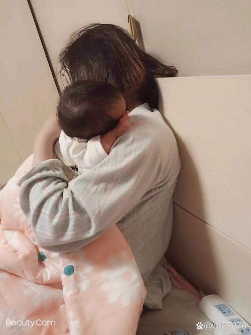 疲惫的母亲抱着婴儿在窗边发呆