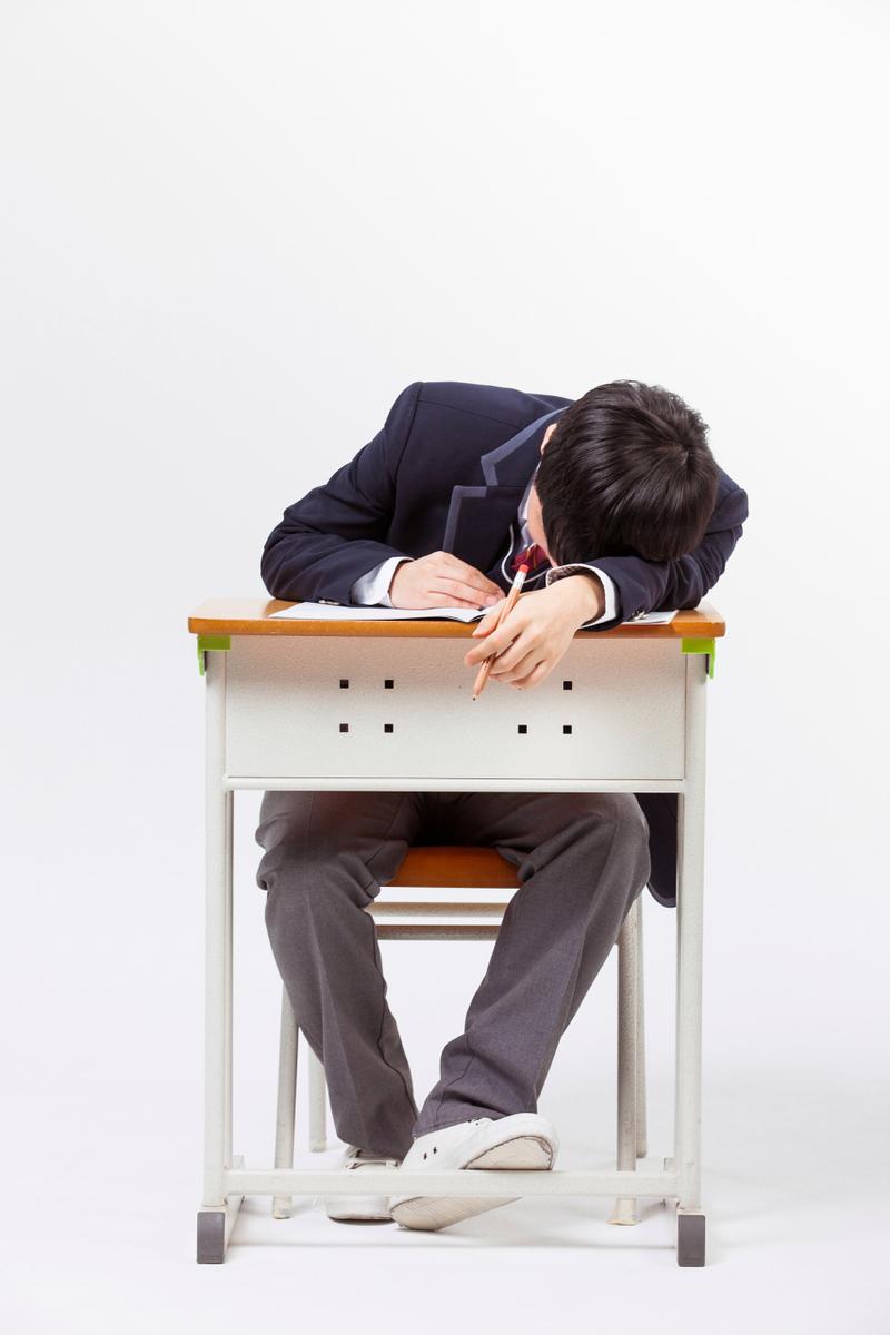 疲惫的小学生趴在桌上不想参加课外班