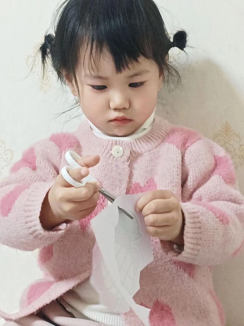小女孩拿着剪刀对着碎布一脸无辜表情