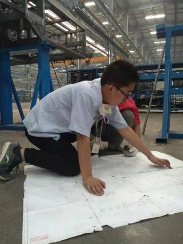 工厂车间里工程师拿着图纸与供应商现场讨论零件细节