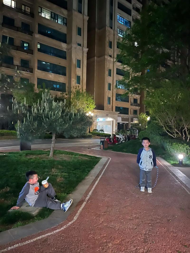 家长陪孩子在小区练跳绳夜景