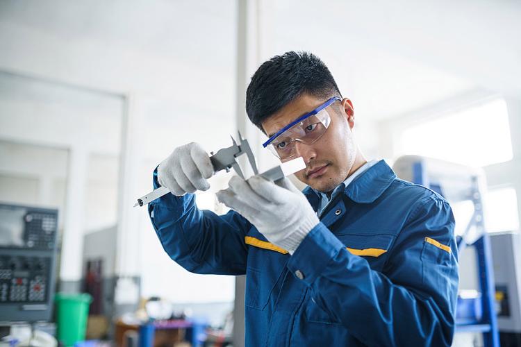 热处理工程师在车间现场用卡尺测量淬火后轴类件变形量