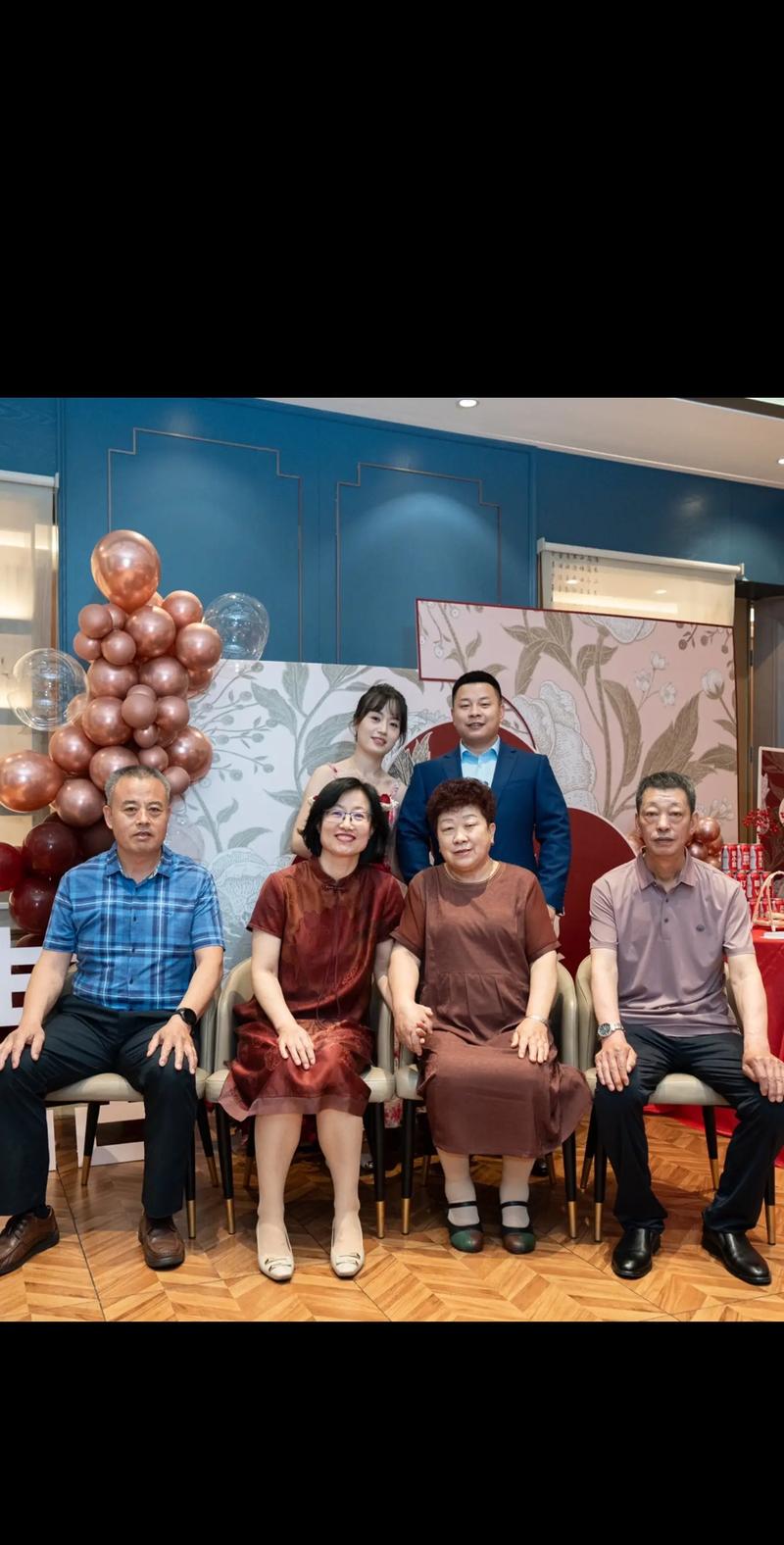 一对新人和双方父母在订婚宴上的合影场景