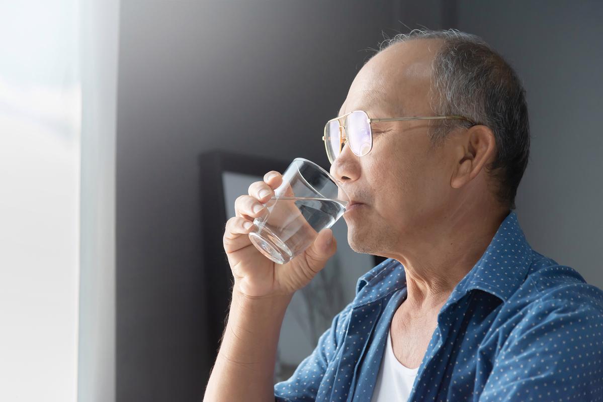 老年人晨起窗边喝水场景图
