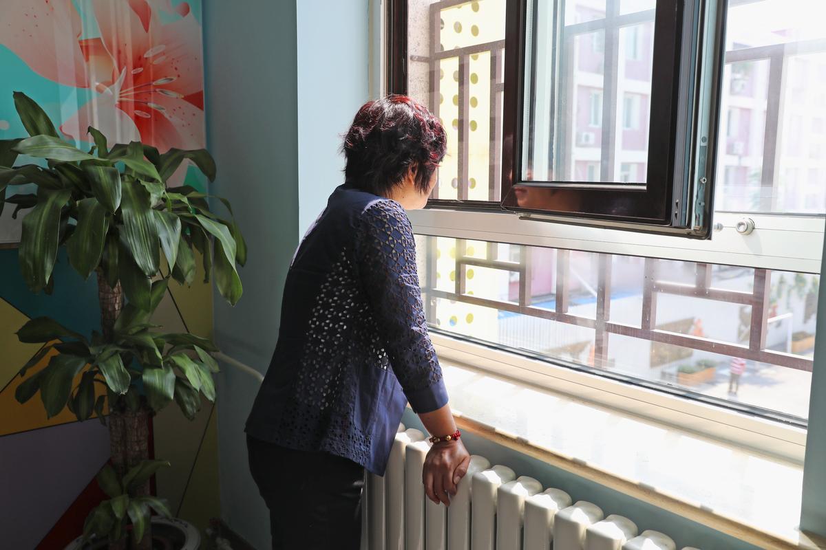 教师在走廊窗边靠着墙看楼下操场的疲惫神态