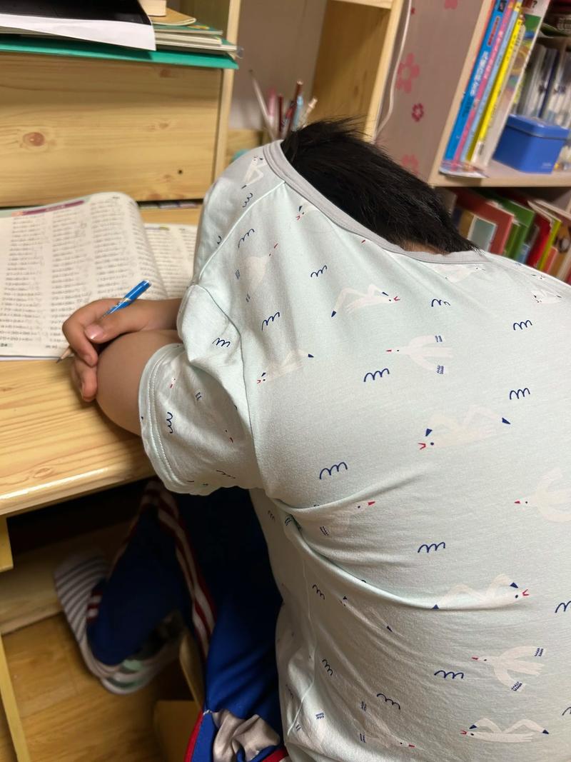 深夜客厅书桌上孩子趴着睡着旁边是散乱的数学卷子