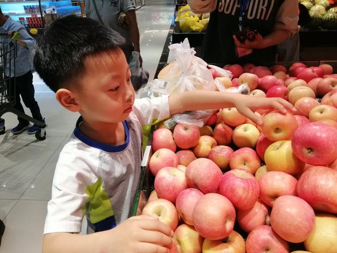 小朋友蹲在菜市场数苹果的亲子照片