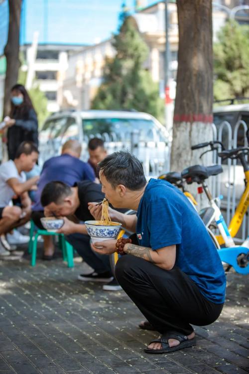 兰州老巷牛肉面馆门口蹲坐吃面的本地人