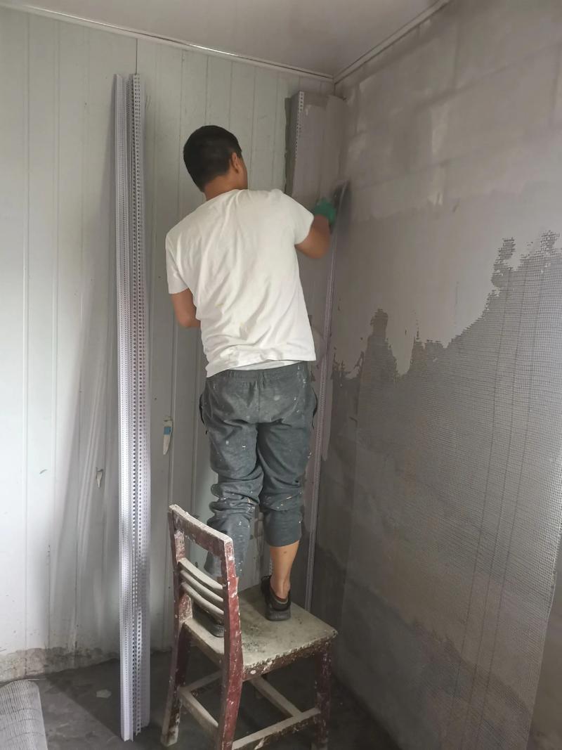 工人正在安装白色石材窗套，墙面已刮腻子未刷漆