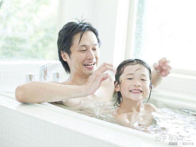 父亲在浴室里用玩具水壶给孩子洗头两人开心大笑