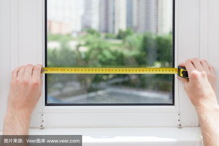 工人用卷尺测量窗户内侧尺寸现场照片