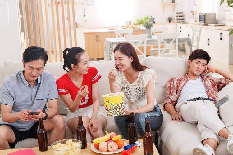 一家人放松地在沙发上吃零食看电视 松弛感育儿家庭时刻