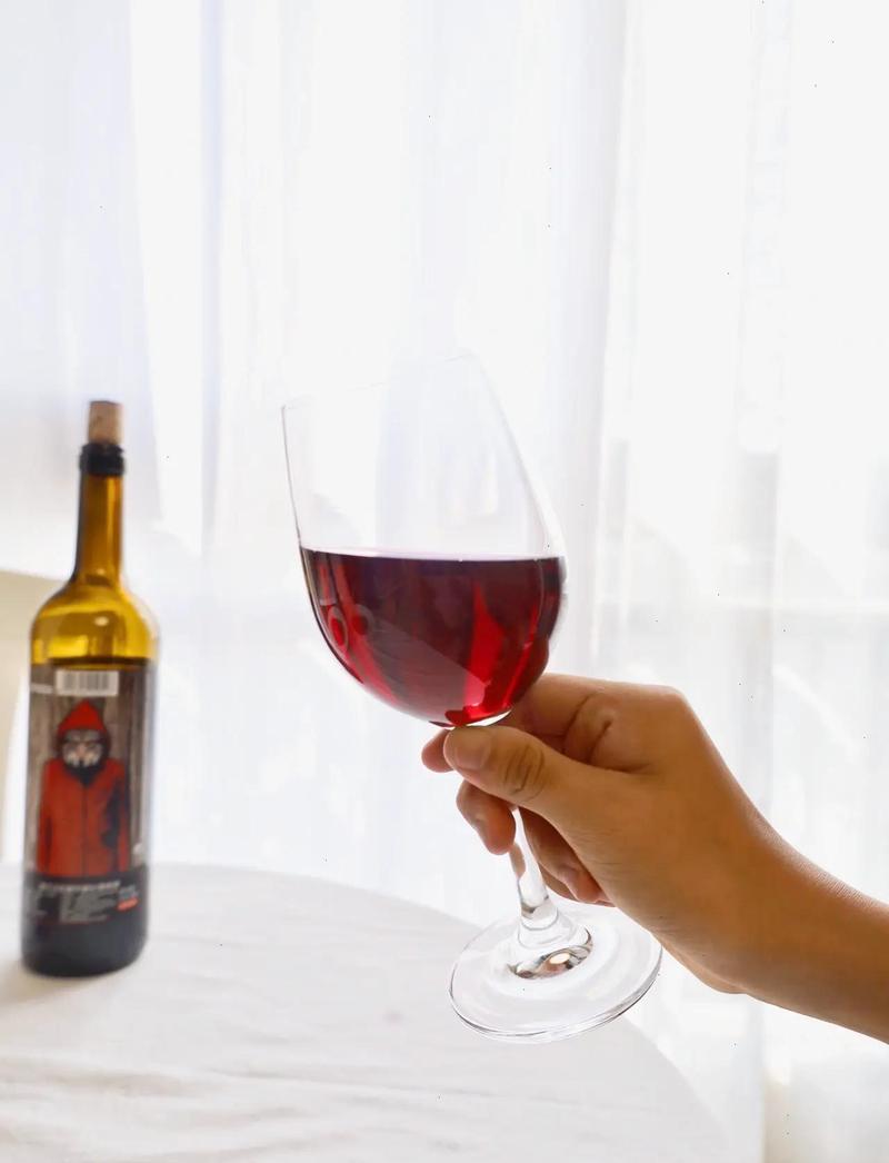 品酒师手持红酒杯观察酒液颜色与挂杯