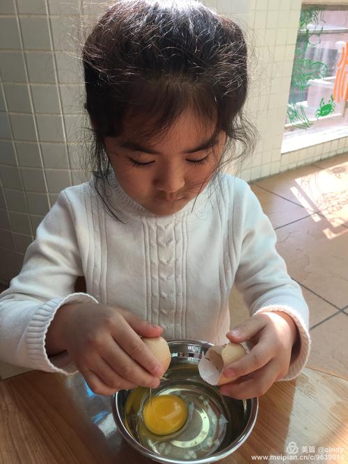 年轻妈妈陪幼儿在厨房观察煮熟的鸡蛋外壳纹理