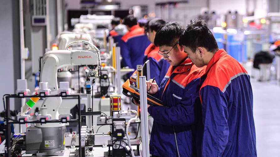 企业师傅正指导学徒检查工业机器人