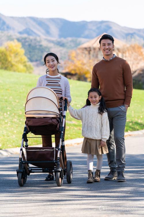 年轻夫妻推婴儿车在公园约会的温馨场景