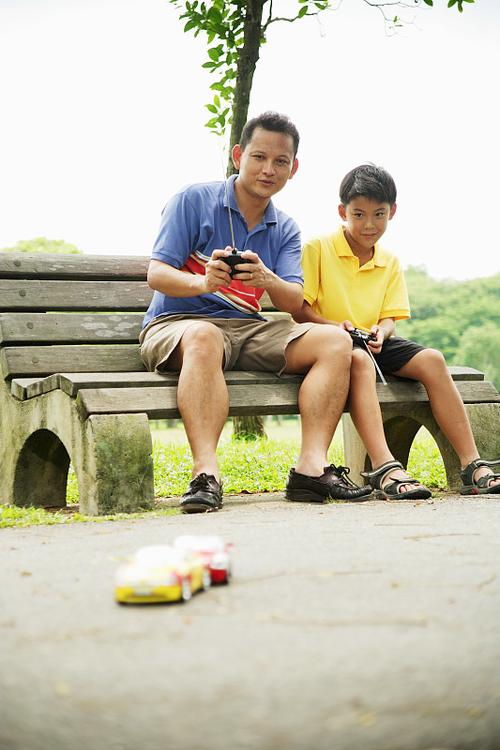 父亲与孩子在户外玩遥控车,孩子不感兴趣