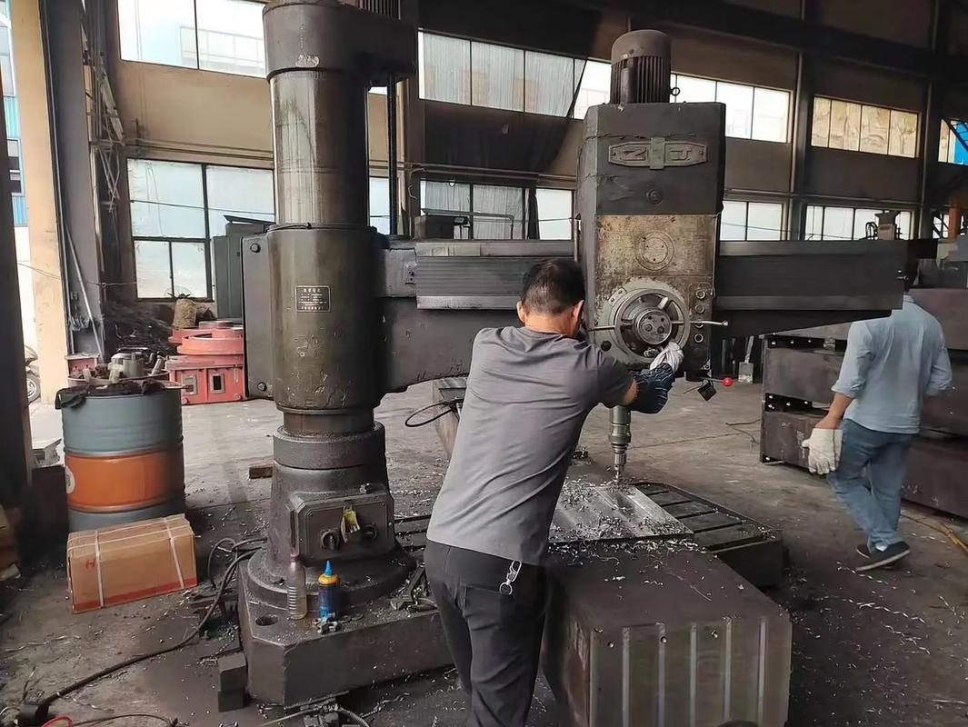 车间内摇臂钻床正在加工大型工件,冷却液飞溅