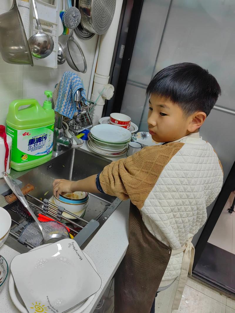 孩子系着围裙 在厨房切菜 略显笨拙