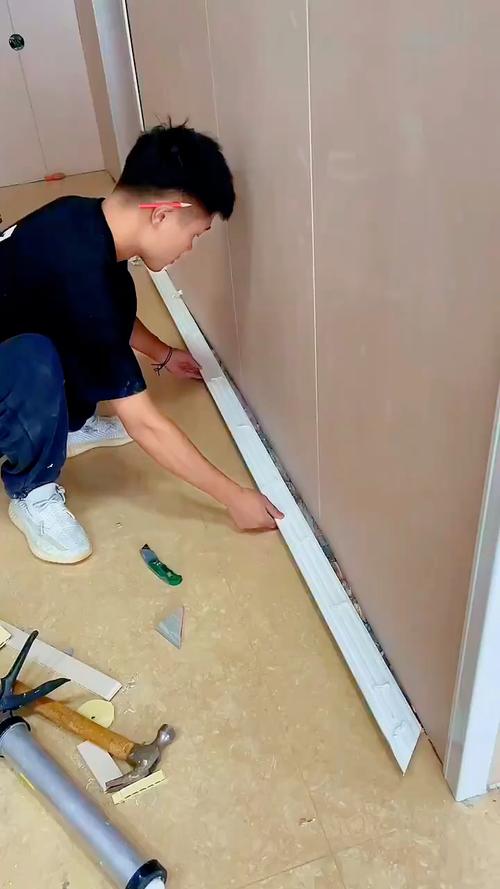 装修工人正在安装门套与踢脚线衔接细节