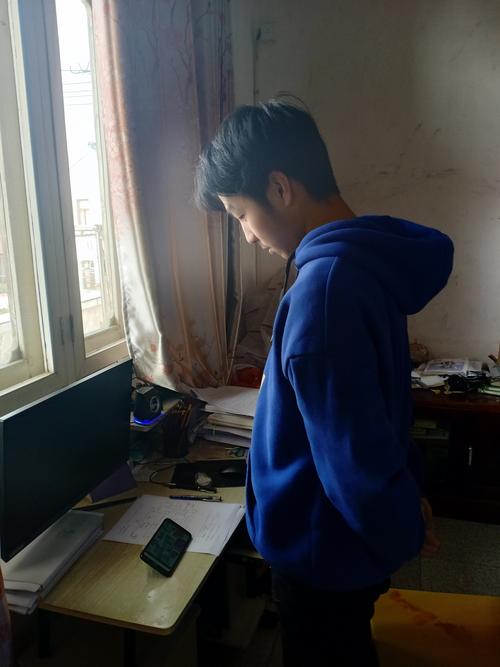 乡村穿蓝校服男孩蹲在教学楼走廊台阶上蹭wifi上网课