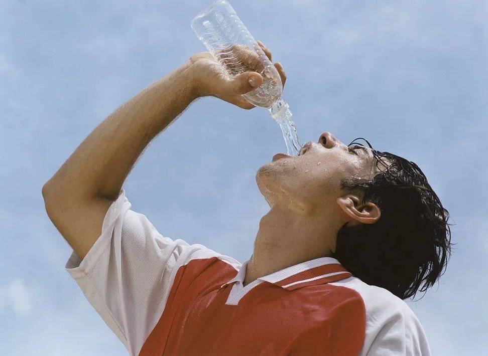 夏天户外满头大汗的人仰头猛灌瓶装冰水