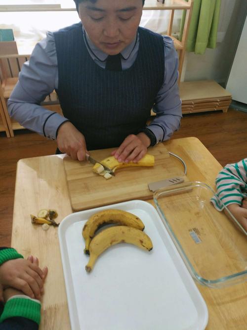 幼儿使用安全刀具切香蕉的场景