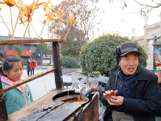 老城巷口捏糖人爷爷给小孩递糖人