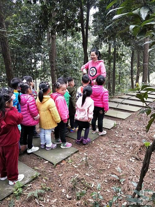 森林幼儿园老师帮小朋友整理被树枝勾住的外套