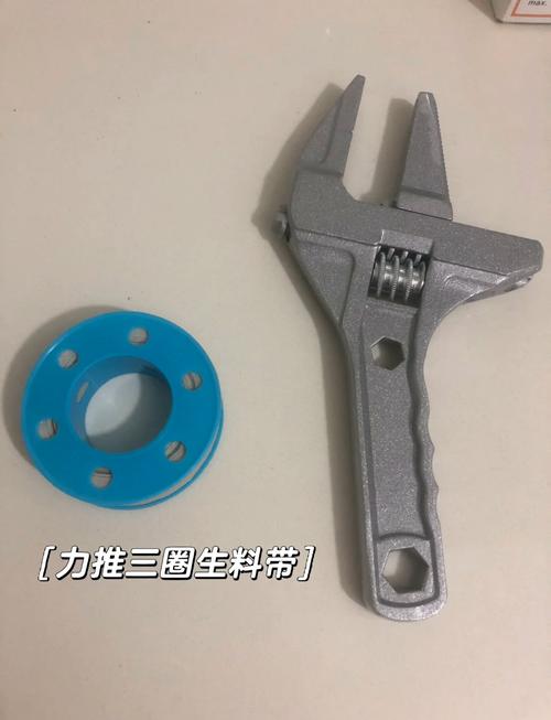 厨房水槽下方水管漏水细节，扳手和生料带散落旁边