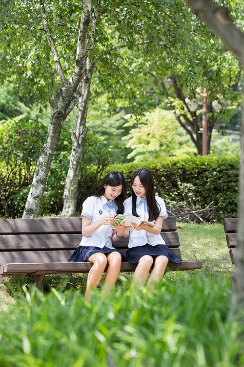 两个十岁小学生坐在公园长椅聊天背影