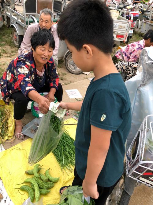 老旧小区便民市集老人给帮忙摆货的小孩递沃柑