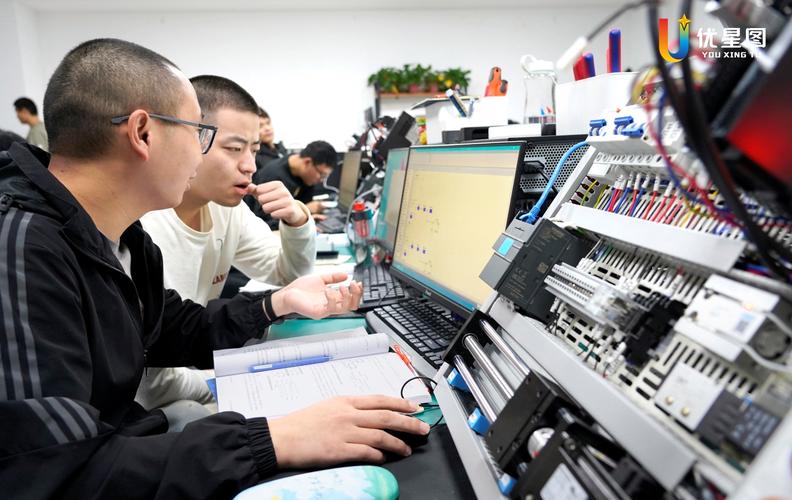 高校教授在工厂车间与学生查看流水线产品质量检测屏幕