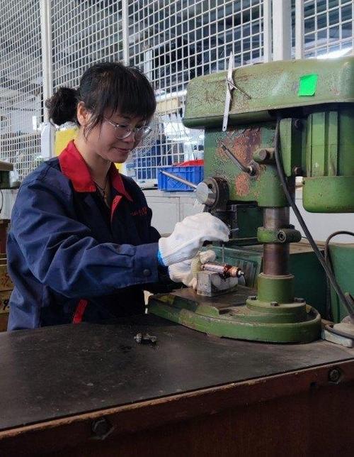 工厂女工胸前别着栀子花在机床前操作
