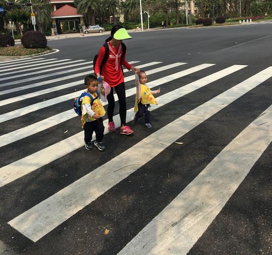 家长陪3岁儿童沿着人行道地砖格子走路的日常场景
