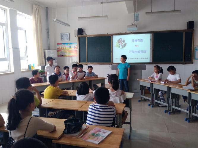 小学生课堂辩论会双方举牌交流场景图