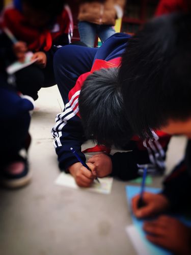 小学生在走廊蹲着手揉皱抄写作业纸的场景