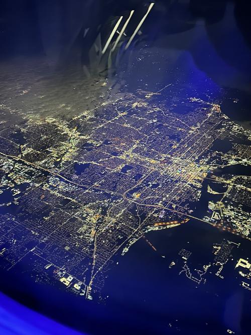 电脑屏幕显示着实时航班地图,密密麻麻的飞机图标,窗外是夜空