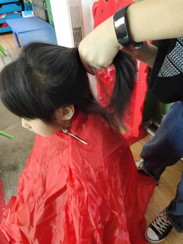 1岁幼儿坐在儿童理发椅上攥着安抚玩偶的实拍