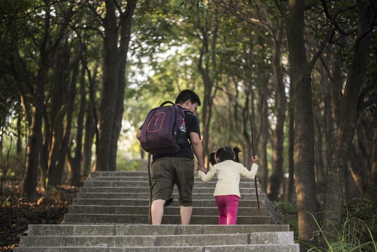 父女户外爬山路边休息背影