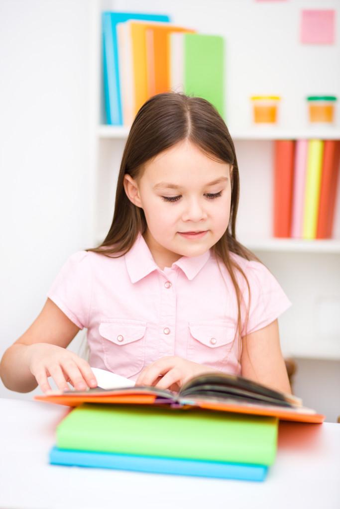 小学低年级孩子坐在书桌前翻英语课本的侧脸