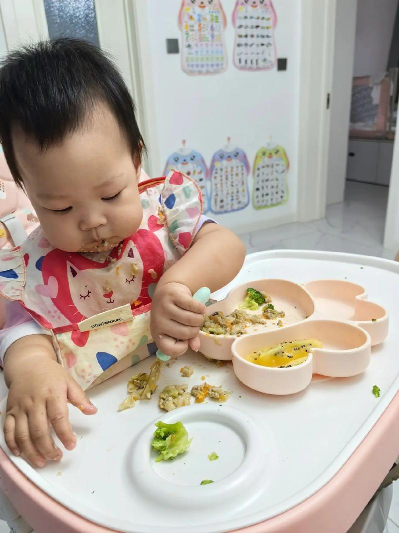 6个月大宝宝坐在餐椅里伸手抓勺子好奇辅食